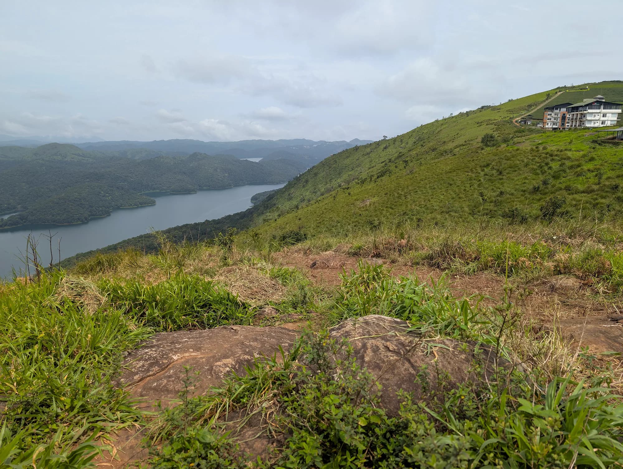 Green hills overlooking a reservoir with a ridge-top building